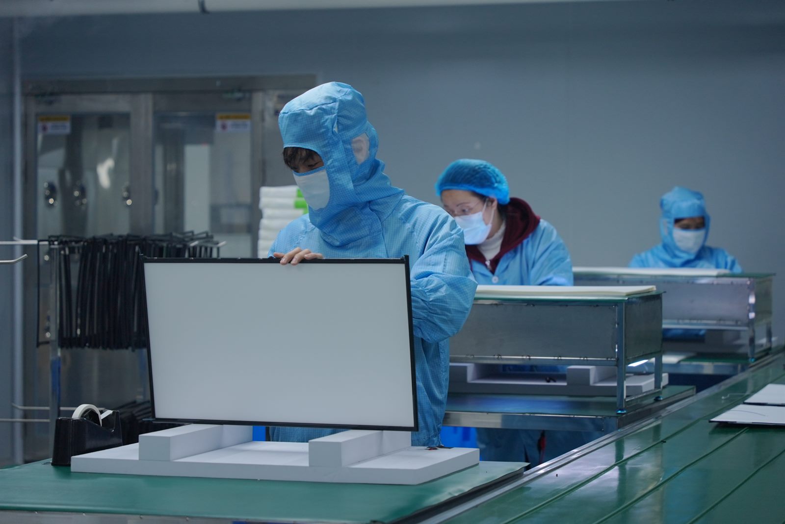 Assembly line workers performing monitor panel quality checks