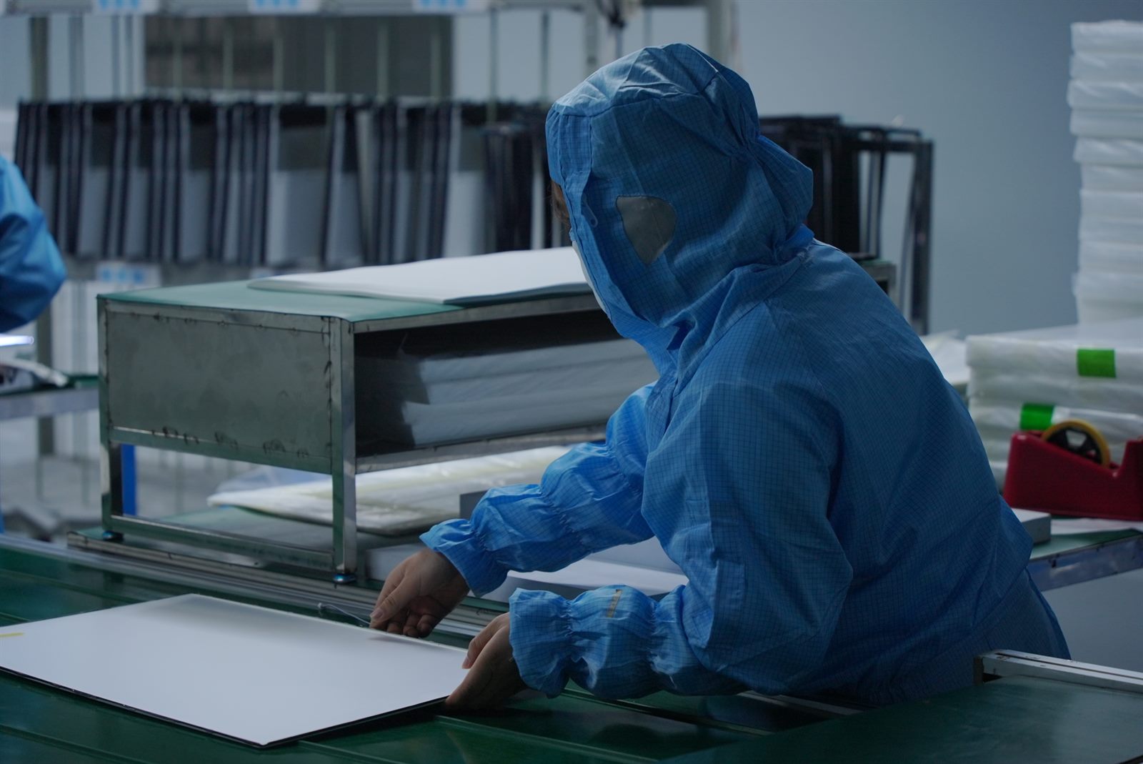 Operator inspecting a monitor panel in a clean-room workstation