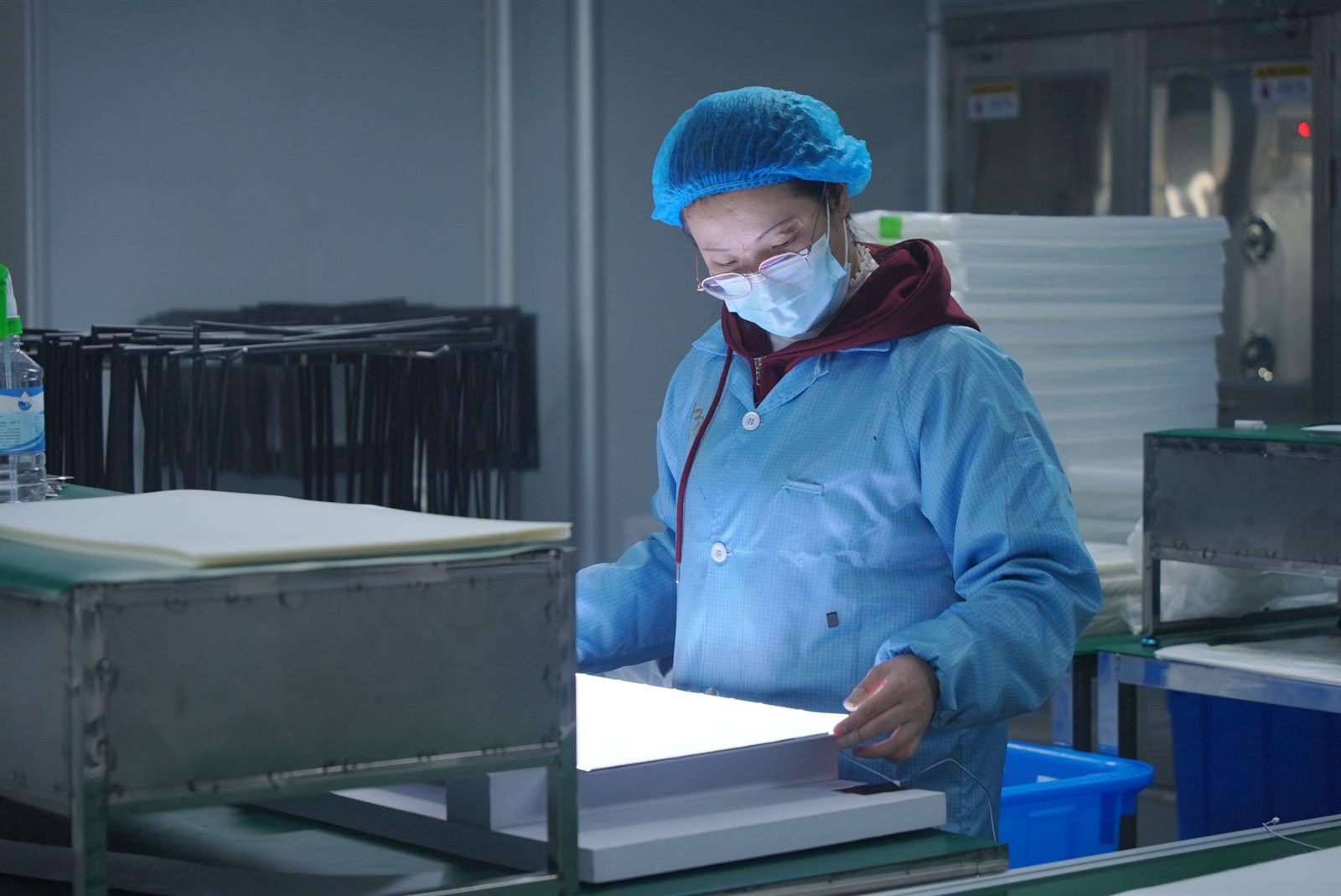 Worker checking an illuminated monitor panel during assembly